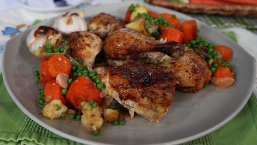 Roasted one-pot whole chicken dinner with spuds, peas, carrots and onions