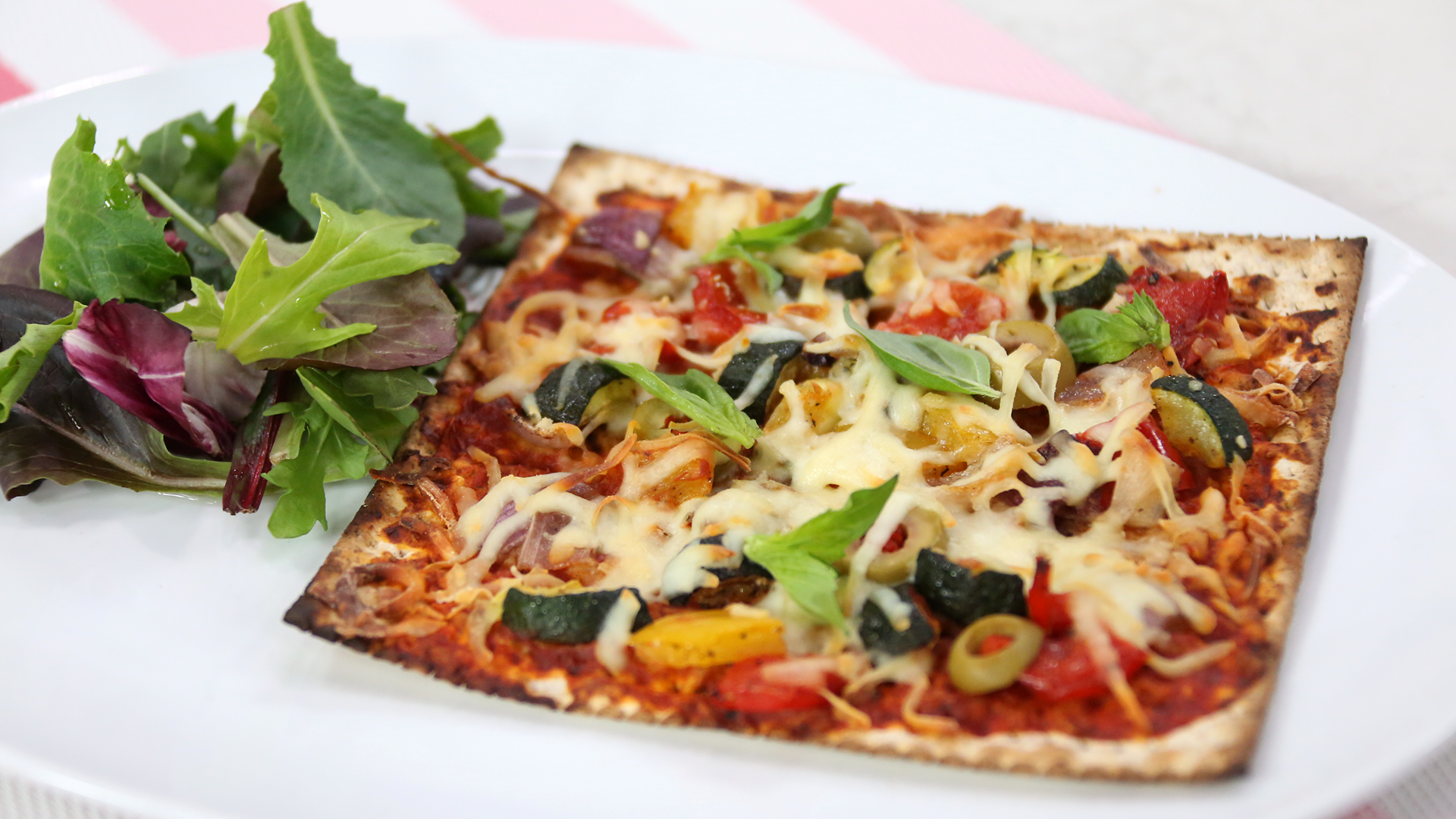 Vegetarian matzah pizza with bell peppers, olives, zucchini and red onion