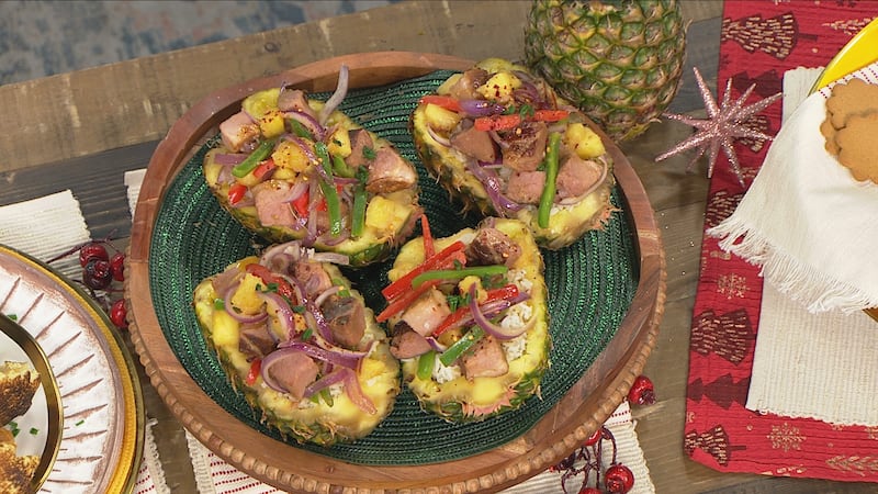 pineapple that has had the fruit removed (just the outer shell) filled with white jasmine rice, chunks of pink ham, green and red peppers, and red onions