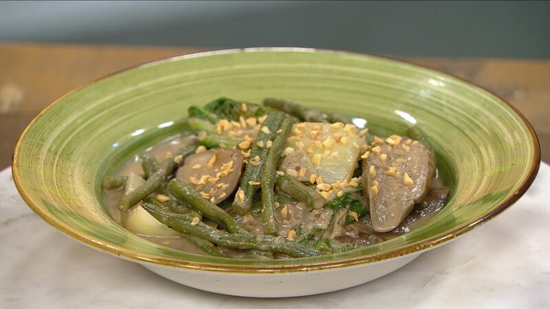 Slices of egg plant, bok choy, long green beans, topped with garlic chip seasoning in a green bowl